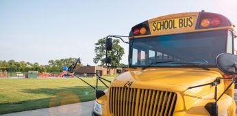 Yellow school bus parked next to playground