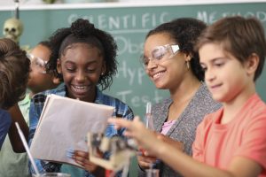 Junior high age school students conduct science experiments in classroom.